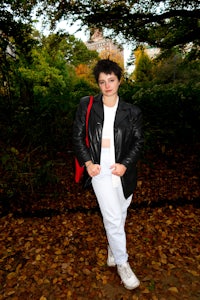 a woman wearing a black leather jacket and white pants