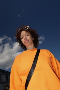 a woman in an orange sweatshirt with a backpack