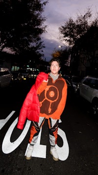 a man in an orange jacket standing on a street
