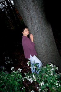a woman leaning against a tree